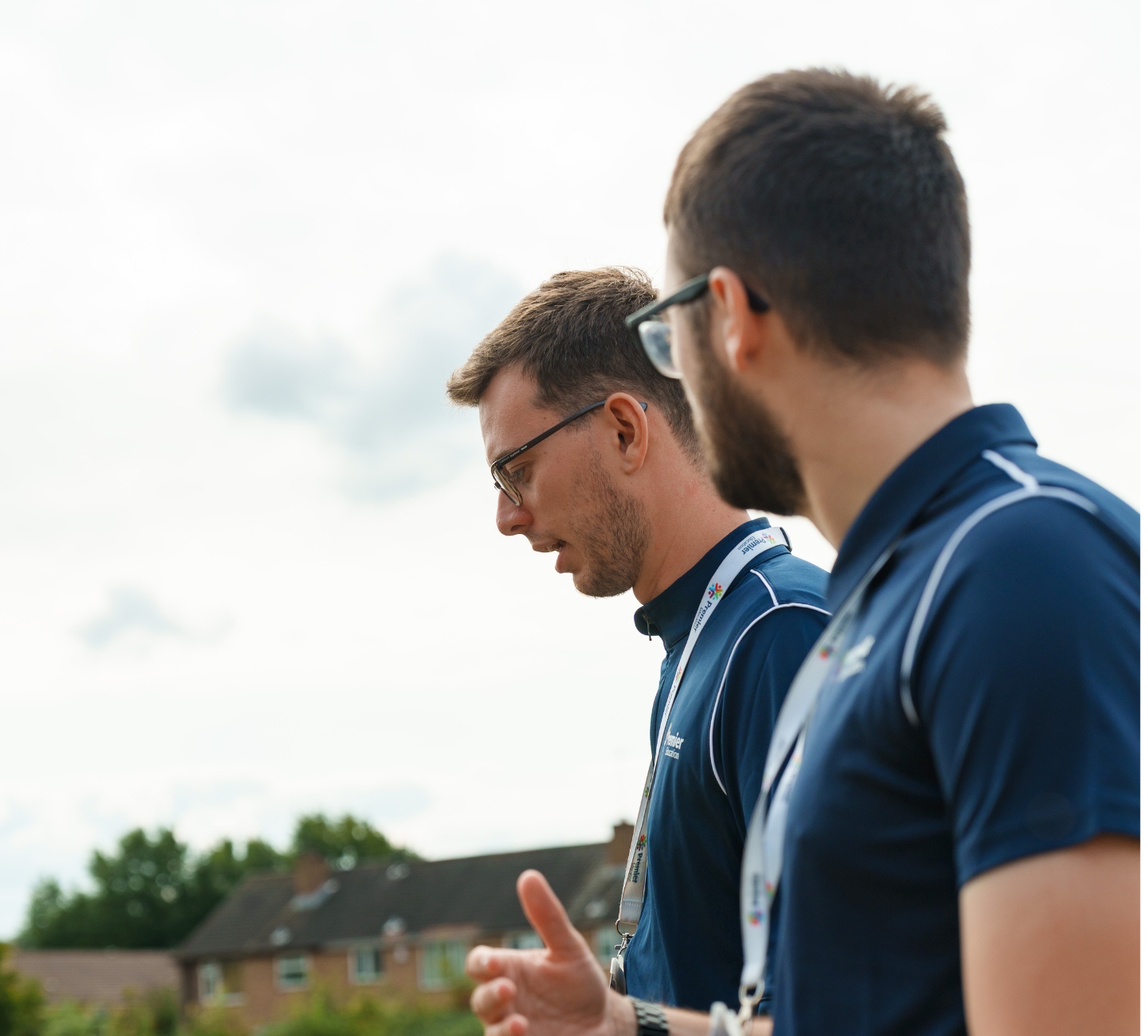 Two men in Premier Education kit walking and talking.